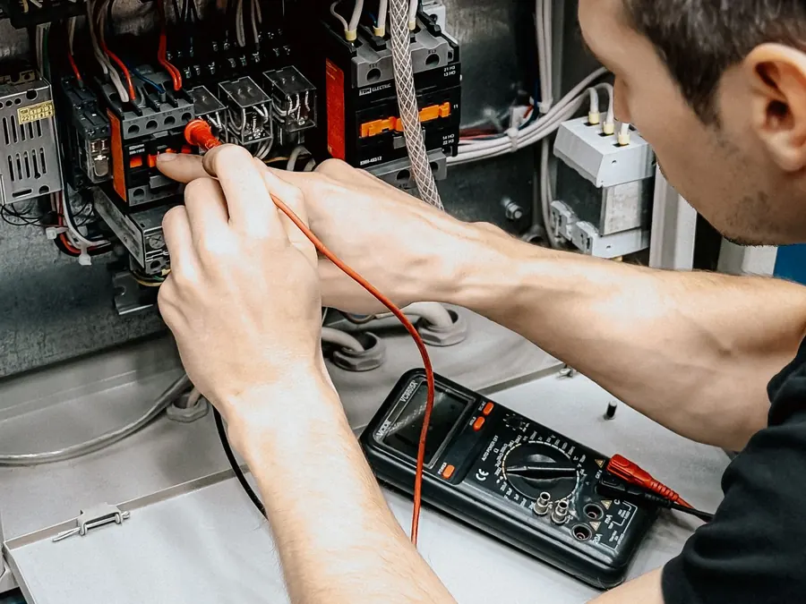 Técnico testando quadro elétrico com multímetro